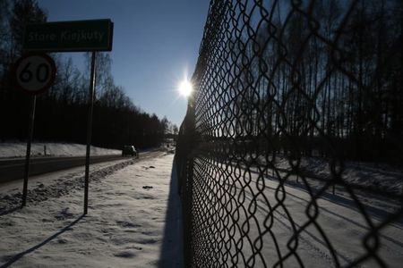 © Reuters. Cars pass by barbed wire fence surrounding a military area in Stare Kiejkuty village, close to Szczytno in northeastern Poland