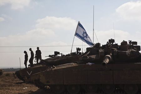 © Reuters. Soldados israelenses em cima de um tanque estacionado próximo à fronteira com a Faixa de Gaza