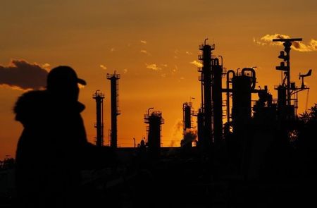 © Reuters. A man walks past chimneys at an industrial district during sunset in Tokyo