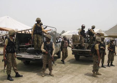 © Reuters. Pakistani soldiers stand guard as people, who fled the military offensive against militants in North Waziristan, receive food supply from the army in Bannu