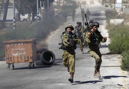 © Reuters. Soldados israelenses correm durante confronto com manifestantes palestinos perto de Ramallah