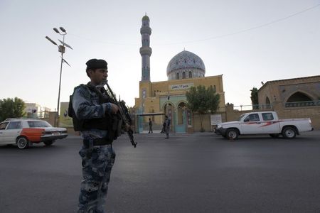 © Reuters. An armed Iraqi policeman stands guard outside a Sunni mosque during Eid al-Fitr prayers in Baghdad