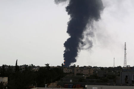 © Reuters. Fumaça emana de local em que um foguete atingiu um tanque de amarzenamento de combustível, na estrada que dá acesso ao aeroporto de Trípoli, na Líbia  