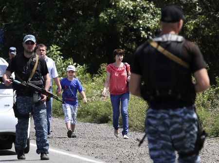 © Reuters. Moradores caminham ao lado de rebeldes pró-Rússia armados nos arredores de Shakhtarsk, na região de Donetsk, leste da Ucrânia 