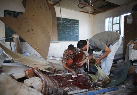 © Reuters. Palestinos coletam partes de corpos em uma sala de aula de uma escola atingida por ataques terrestres de Israel, em Jebalya, na Faixa de Gaza