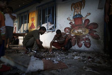 © Reuters. Palestinos coletam restos de corpos em uma escola gerida pela ONU atingida por um ataque terrestre de Israel, em Jebalya, na Faixa de Gaza