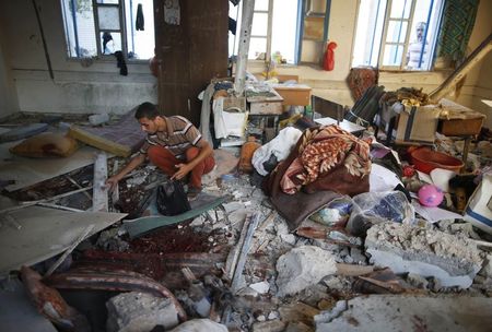 © Reuters. Palestinos coletam partes de corpos em uma sala de aula de uma escola atingida por ataques terrestres de Israel, em Jebalya, na Faixa de Gaza