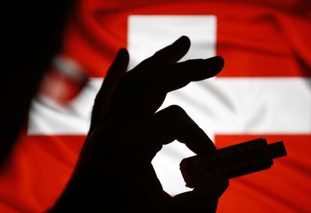 © Reuters. A man poses holding a USB datastick in his hand in front of the Swiss flag in this photo illustration taken in the central Bosnian town of Zenica