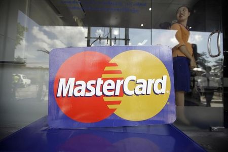© Reuters. An employee stands behind a MasterCard logo during the launch of the international credit card issuer's first ATM transaction in Myanmar, in Yangon