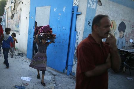 © Reuters. Garota palestina carrega seus pertences ao sair de uma escola gerida pela ONU, que abrigava palestinos desabrigados pela ofensiva terrestre israelense, em Jebalya, na Faixa de Gaza 