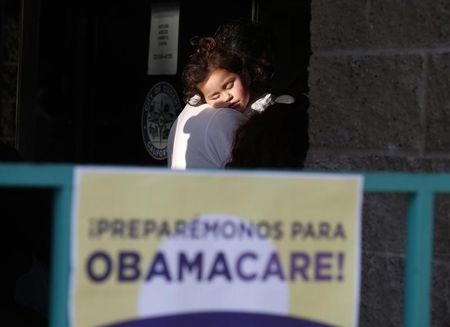 © Reuters. Esparza sleeps in the arms of her grandfather as they wait in line at a health insurance enrollment event in Cudahy, California