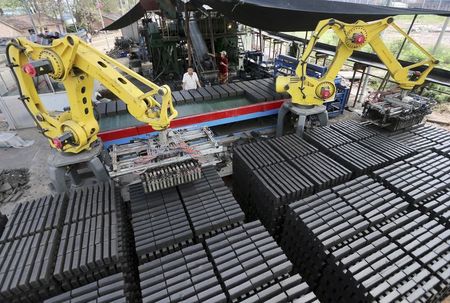 © Reuters. Workers look at machines moving newly made raw bricks at a factory in Huaibei