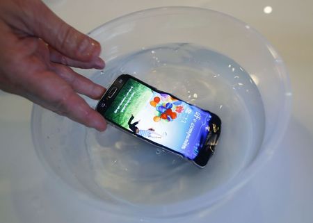 © Reuters. P2i's CEO Carl Francis demonstrates a mobile phone functioning in water, during an interview in Singapore