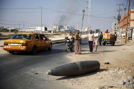 © Reuters. Palestinos observam uma bomba não detonada lançada pelas forças israelenses contra a cidade de Deir Al-Balah, na região central da Faixa de Gaza