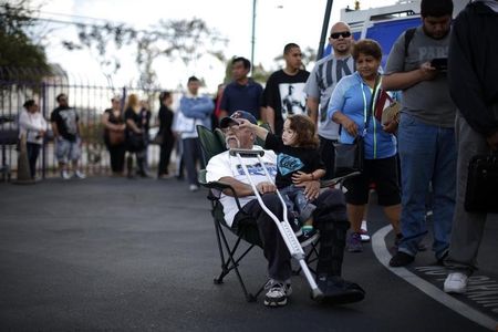 © Reuters. Juan Ortiz, 67, and his eighteen-month-old grandson Joshua Lopez wait in line at a health insurance enrollment event in Commerce