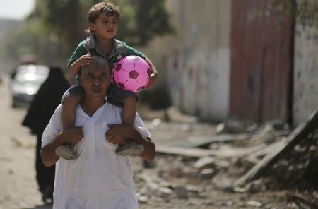 © Reuters. Palestino carrega seu filho na Cidade de Gaza