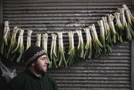 © Reuters. A vendor hangs vegetables in front of a shop in a bazaar in northern Tehran