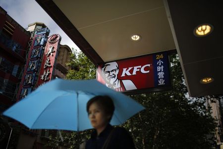 © Reuters. A woman walks by a KFC store in downtown Shanghai