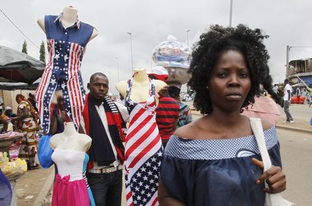 © Reuters. A street vendor holds mannequins wearing clothes depicting the U.S. national flag in the streets of Abidjan