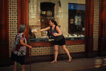 © Reuters. A gift shop's worker cleans the glass of a shop at La Bola street in downtown Ronda