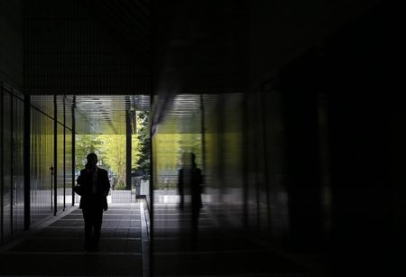 © Reuters. Man using a mobile phone walks down a corridor of a building at a business district in Tokyo