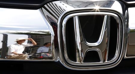 © Reuters. Man are reflected on a Honda Motor car outside the company showroom in Tokyo