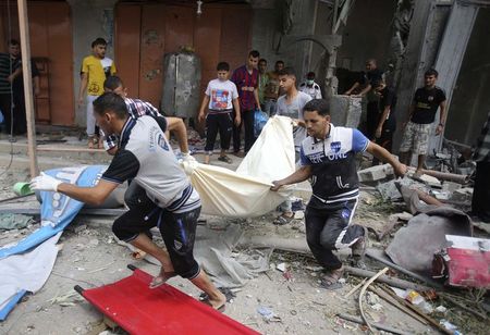 © Reuters. Palestinos carregam o corpo de uma mulher retirado dos escombros de uma casa que segundo testemunhas foi destruída em um bombardeio de Israel, na Faixa de Gaza 