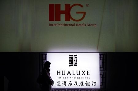 © Reuters. A woman stands near an illuminated sign for Hualuxe Hotels and Resorts during its official launch inside the Forbidden City in Beijing