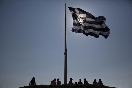 © Reuters. Tourists stand under a Greek flag atop the hill of the Acropolis in Athens