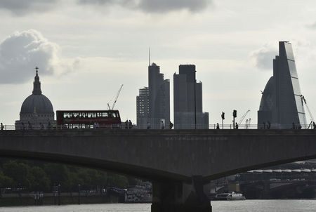 © Reuters. Workers cross Waterloo Bridge with the City of London seen behind, in London