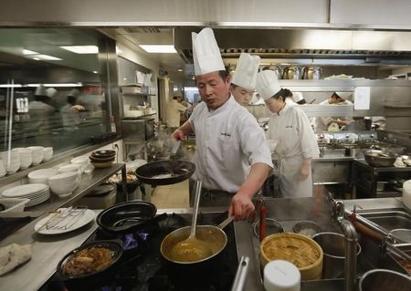 © Reuters. Chiefs cook meal at restaurant inside shopping mall in wealthy district in Beijing