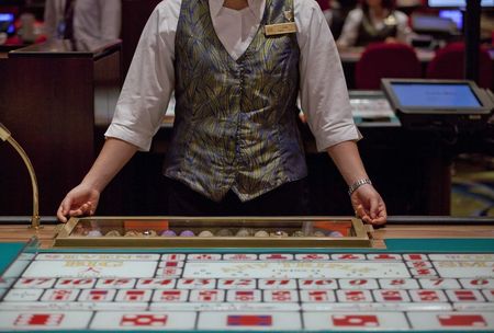 © Reuters. File photo of a croupier sitting in front of a gaming table inside a casino on the opening day of Sheraton Macao hotel at Sands Cotai Central in Macau