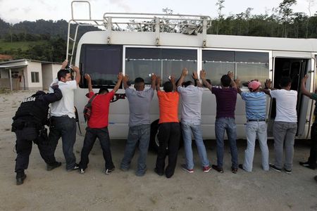 © Reuters. Border patrol police officer frisks passengers of a bus at a checkpoint in Honduras, near its border with Guatemala