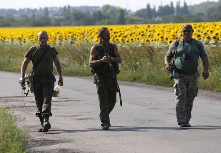 © Reuters. Separatistas pró-Rússia caminham em Rozsypne, perto do local da queda de uma avião da Malásia