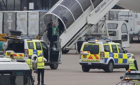 © Reuters. Uomo scortato dalla polizia fuori dal velivolo della Qatar Airways  all'aeroporto di Manchester dopo che un jet della RAF ha scortato il velivolo per un pacco sospetto 