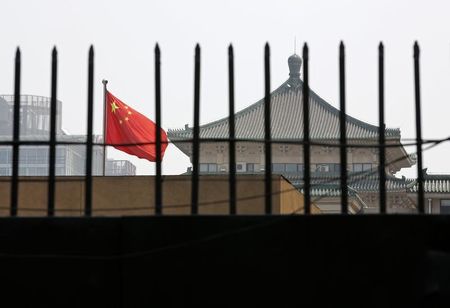 © Reuters. The national flag of China flutters behind a fence of the headquarters of the NDRC in Beijing
