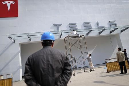 © Reuters. Labourers work on exterior of new Tesla showroom in Shanghai