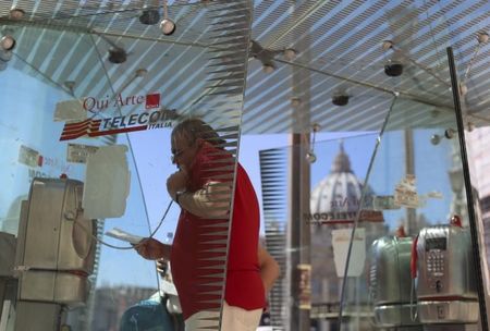 © Reuters. Man uses a Telecom Italia phone booth in front of St Peter's Basilica in Rome