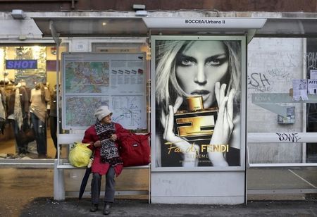 © Reuters. A woman waits at a bus stop in Rome