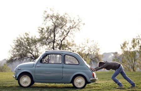 © Reuters. Woman pushes her Fiat 500 car as her dog sits inside, in neighbourhood of Rome