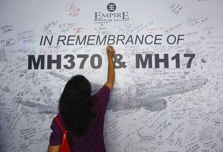 © Reuters. A woman writes a message on a dedication board for victims of the downed Malaysia Airlines Flight MH17 airliner and the missing Flight MH370, in Subang Jaya