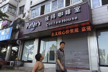 © Reuters. A boy looks up as he walks past the closed coffee shop owned by Canadian couple Kevin Garratt and Julia Dawn Garratt in Dandong, Liaoning province