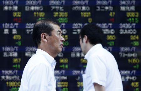 © Reuters. Pedestrians walk past an electronic board showing the various stock prices outside a brokerage in Tokyo