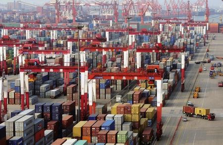 © Reuters. Trucks drive past piles of shipping containers at the Qingdao port in Qingdao