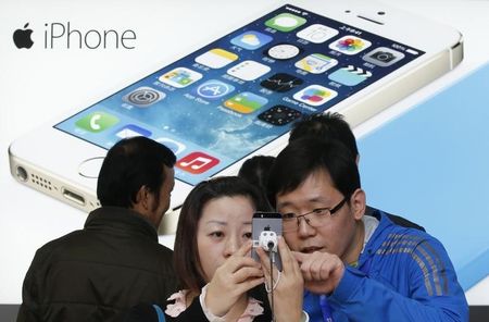 © Reuters. A staff of a China Mobile shop (R) explains a function of the iPhone 5s to a customer in Beijing