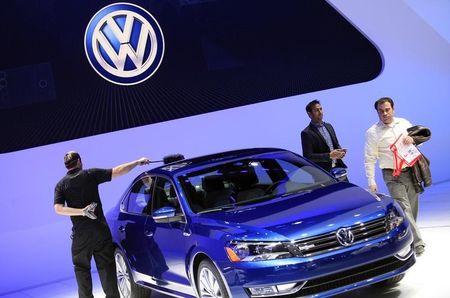 © Reuters. A worker dusts a Volkswagen Passat Blue Motion Concept as visitors look on during the North American International Auto Show in Detroit
