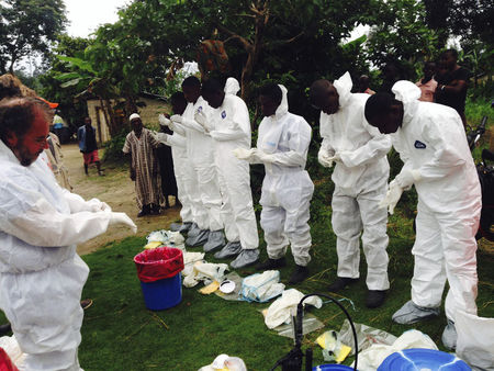 © Reuters. Volunteers prepare to remove the bodies of people who were suspected of contracting Ebola and died in the community in the village of Pendebu