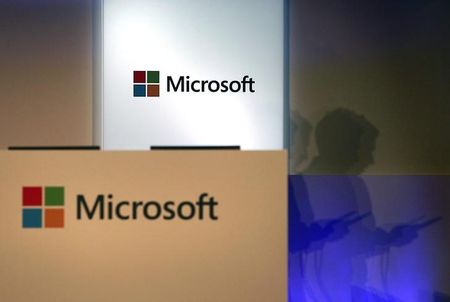 © Reuters. A shadow of a man using his mobile phone is cast near Microsoft logo at the 2014 Computex exhibition in Taipei