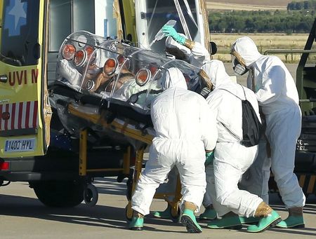 © Reuters. Health workers load Ebola patient, Spanish priest Miguel Pajares, into an ambulance on the tarmac of Torrejon airbase in Madrid