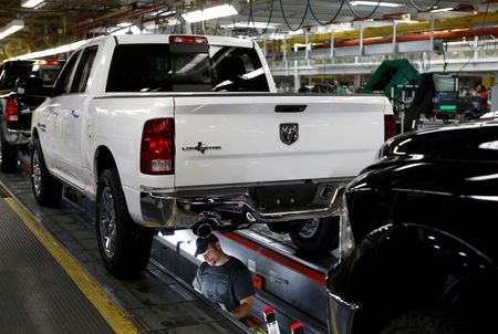 © Reuters. Chrysler Group assembly staff works below 2014 Dodge Ram pickup truck  at the Warren Assembly Plant in Warren